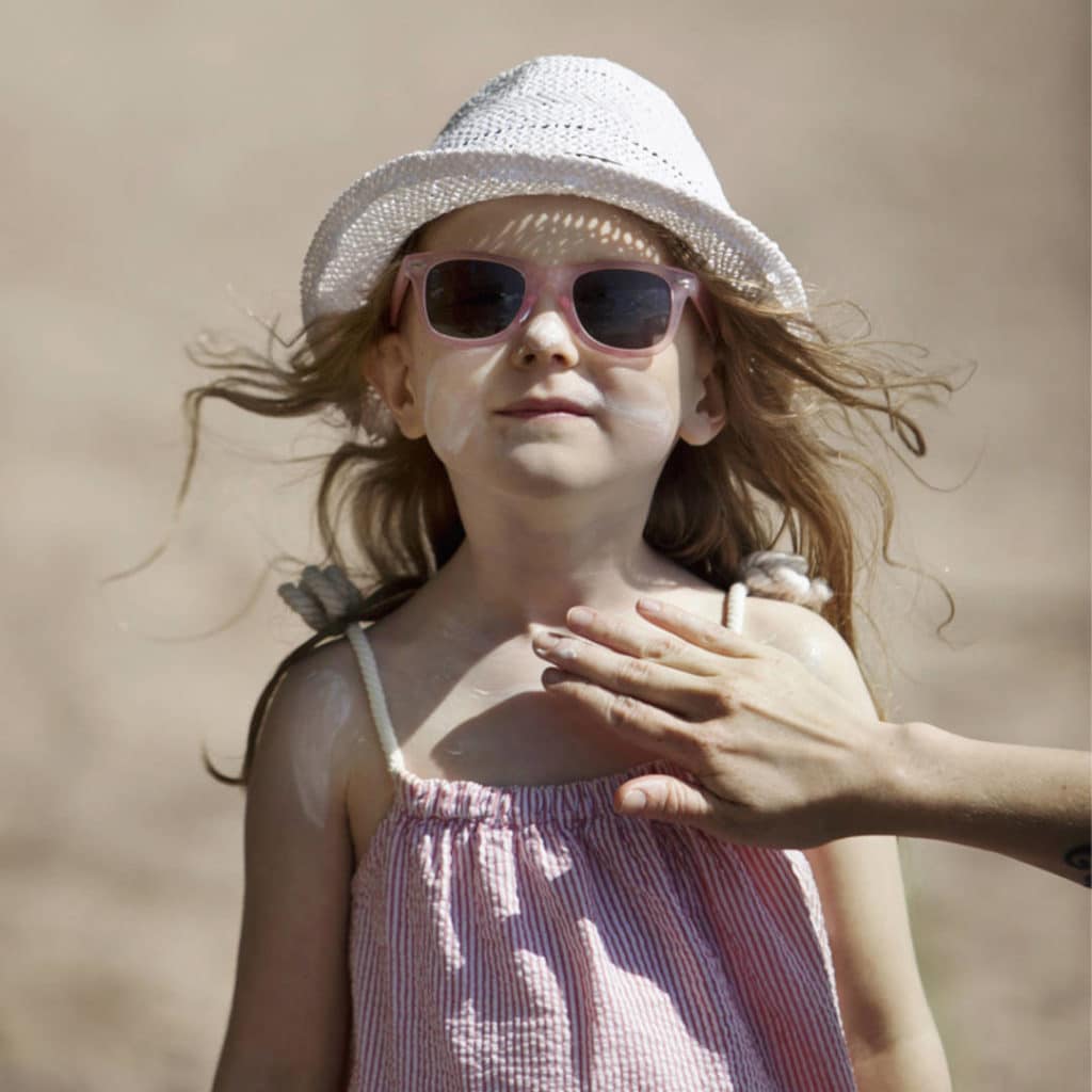 Lapsi, jolla on päässään hattu ja aurinkolasit.