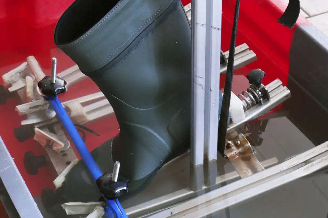 Kumisaapas, jota liikutetaan vesialtaassa testauslaitteella.