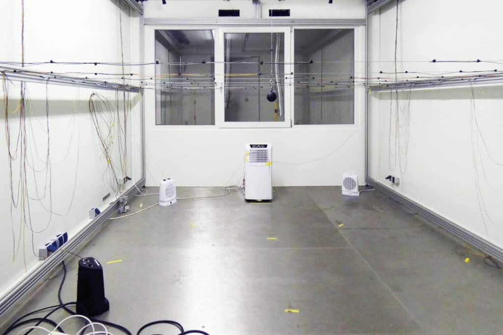 Siirrettävä ilmastointilaite sekä viilennysnopeutta mittaavaa testauslaitteistoa laboratoriossa.