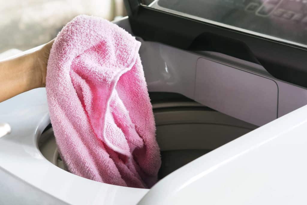 Pyyhe nostetaan päältä täytettävästä pyykinpesukoneesta.