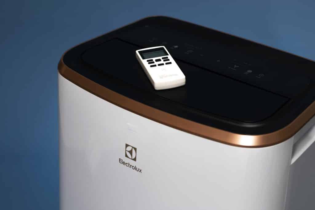 Electrolux-merkkinen siirrettävä ilmastointilaite, jonka päällä on laitteen kaukosäädin.