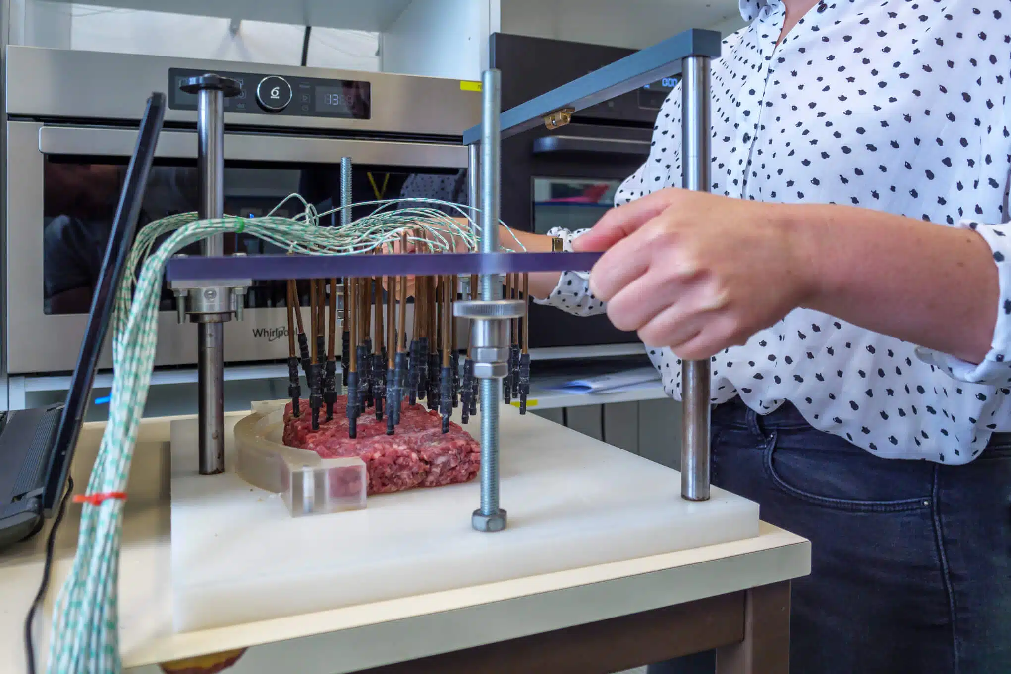 Henkilö mittaamassa sulatetun jauhelihan lämpötilaa testauslaitteella laboratoriossa.