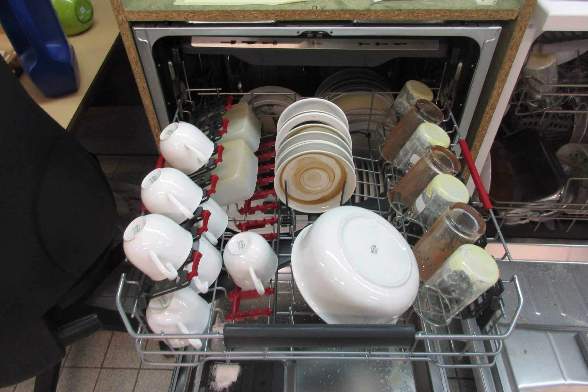 Auki oleva kalustepeitteinen astianpesukone, jonka sisällä on likaisia astioita.