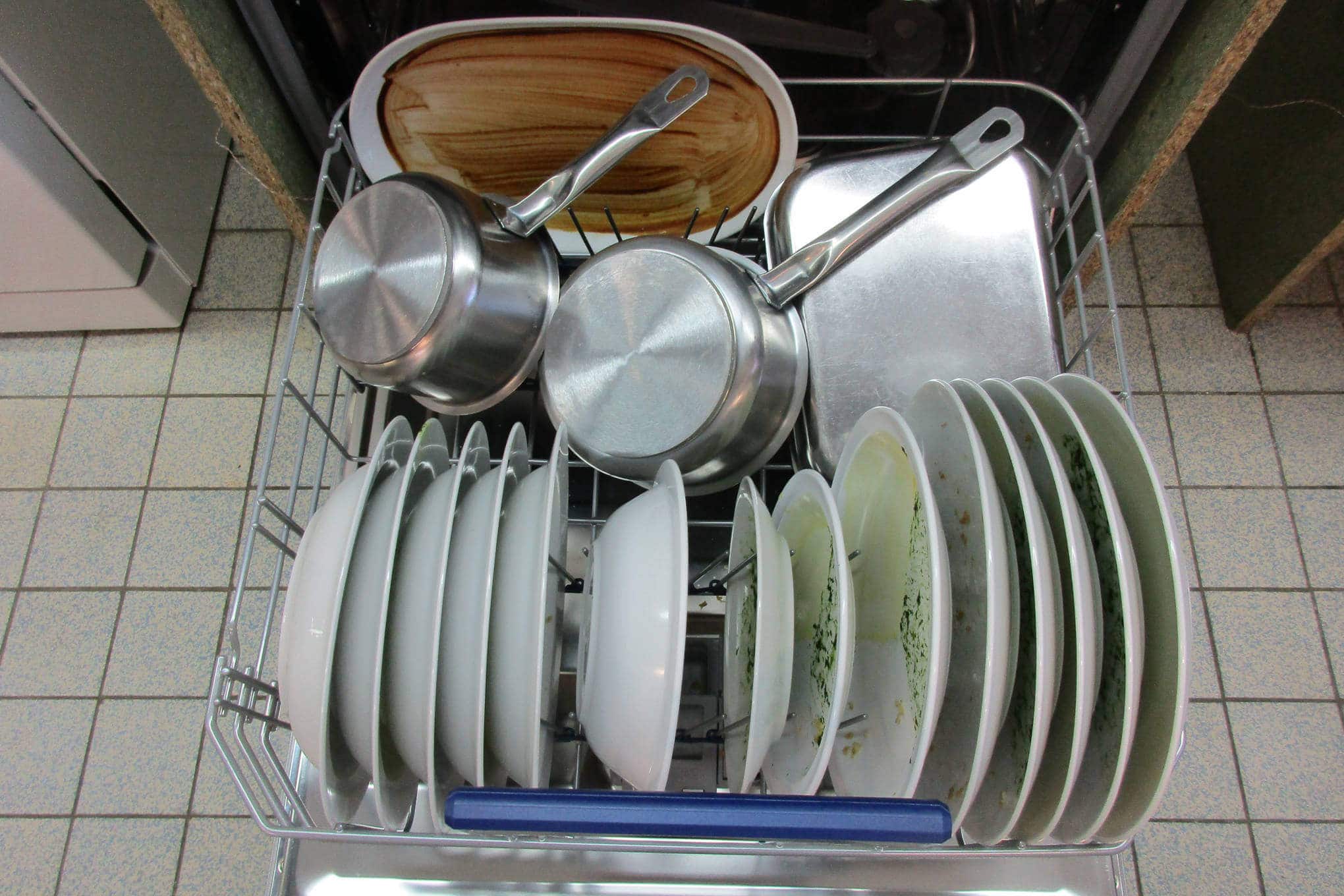 Auki oleva kalustepeitteinen astianpesukone, jonka sisällä on likaisia astioita.