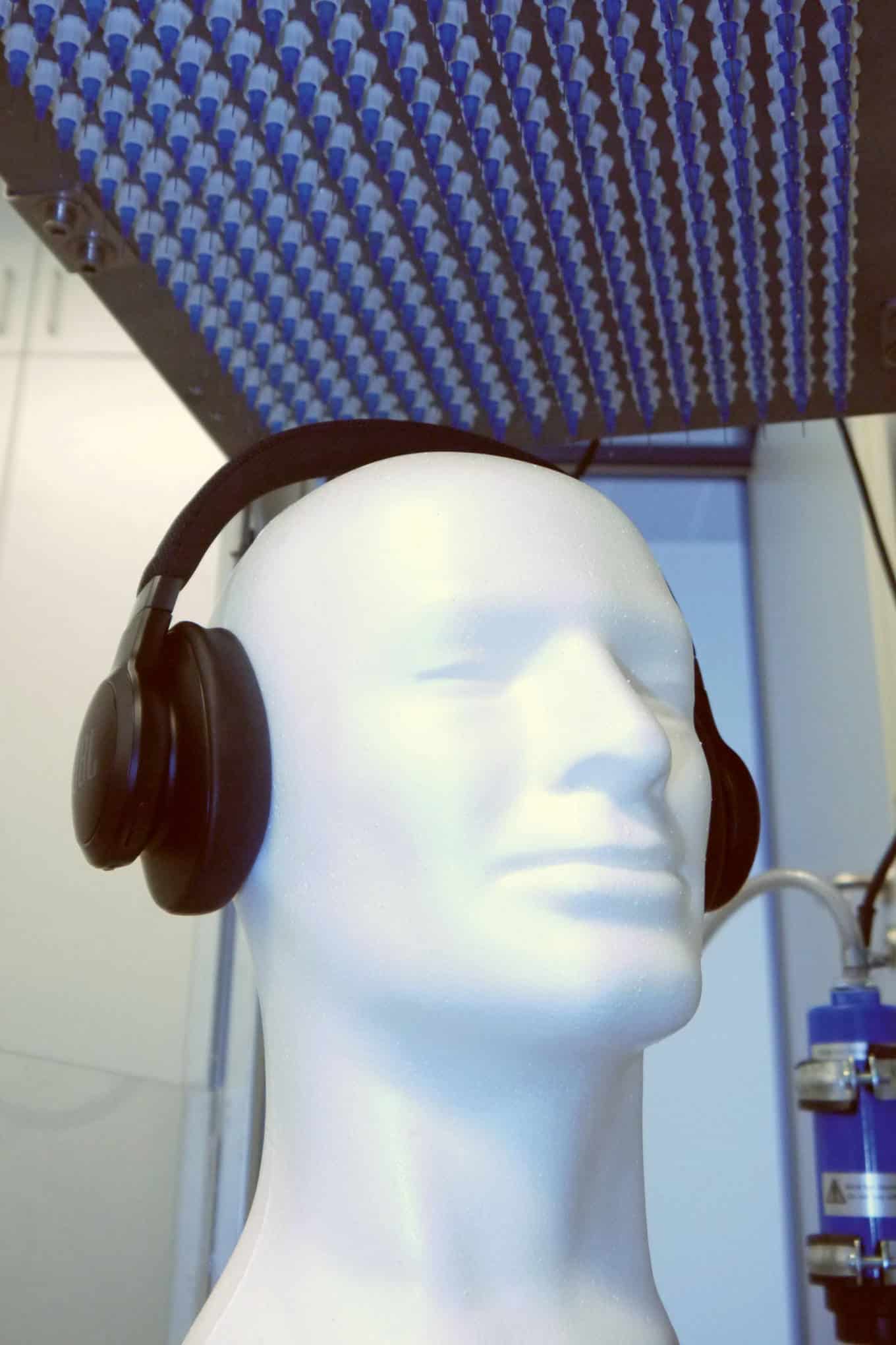Langattomat kuulokkeet ja vesisadetta simuloiva testauslaite laboratoriossa.