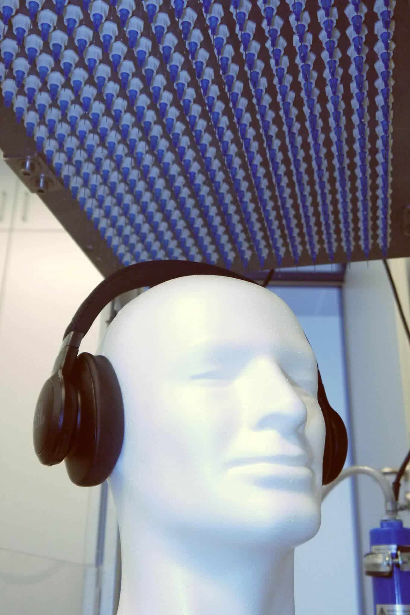 Kuulokkeet ja vesisadetta simuloiva testauslaite laboratoriossa.