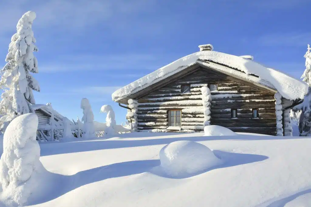 Mökki lumisessa maisemassa.