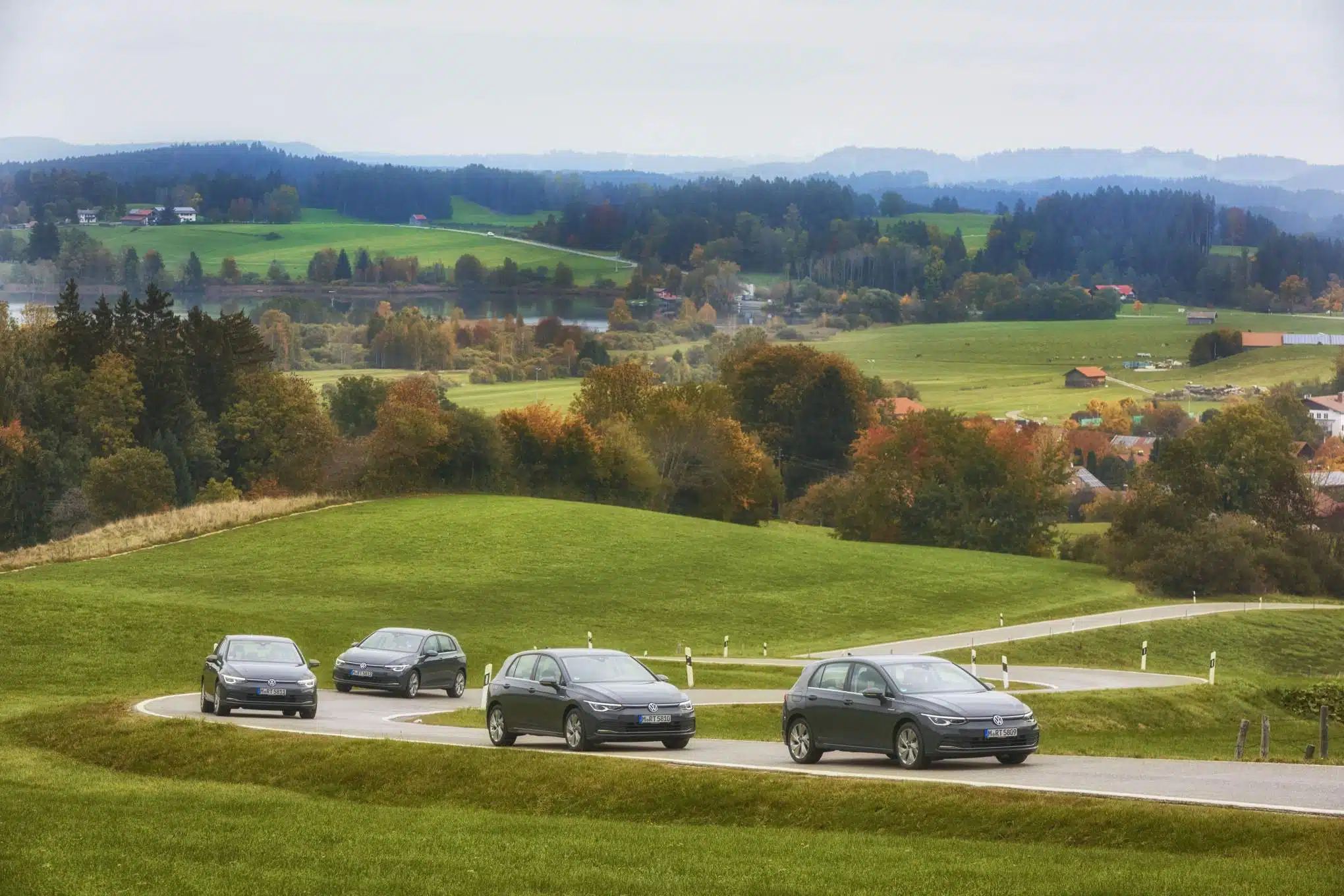 Neljä Volkswagen-merkkistä henkilöautoa mutkittelevalla tiellä.