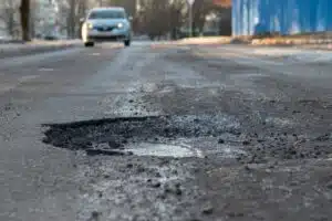 Auto ajaa asfalttitiellä, jossa on reikä.