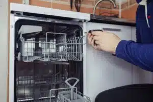 Auki oleva astianpesukone, jonka edessä on henkilö.