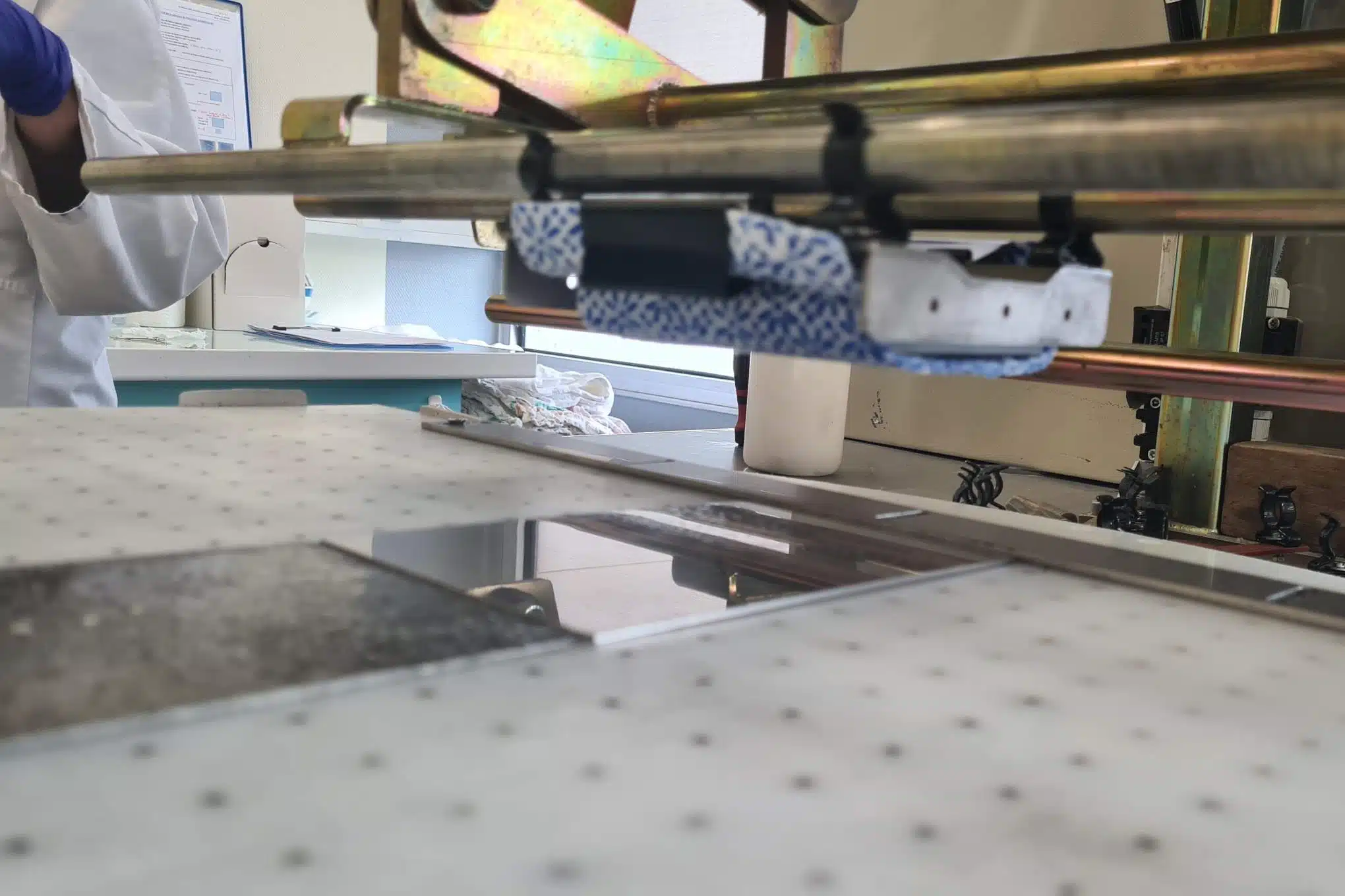Testauslaitteistoa laboratoriossa sekä henkilö, jolla on kädessään suojahanskat.