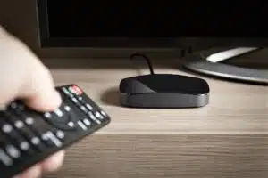 Henkilö osoittaa kaukosäätimellä äly-tv-laitetta.